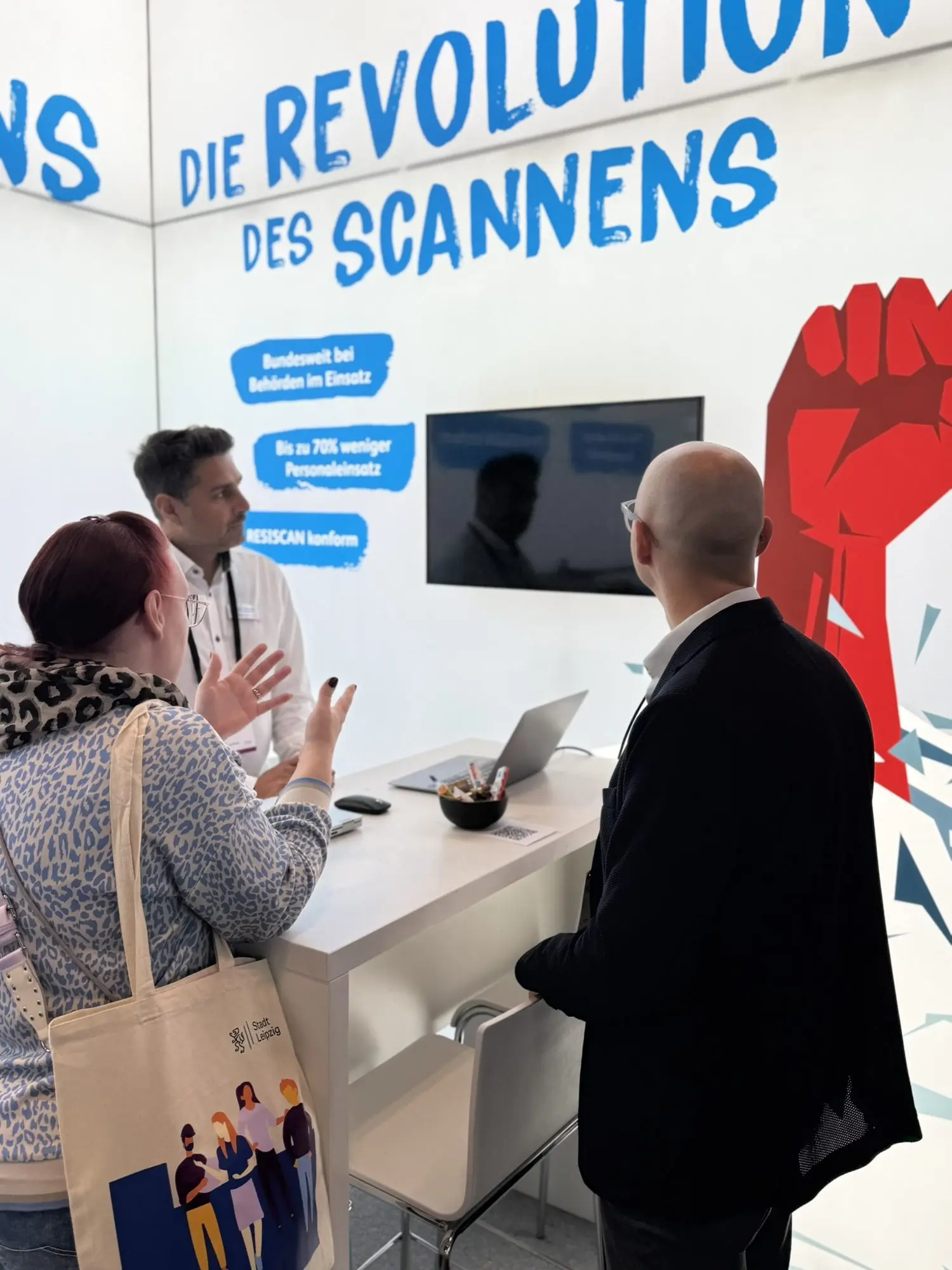 Beratungsgespräch am Stand vor der Markenwand mit der roten Faust