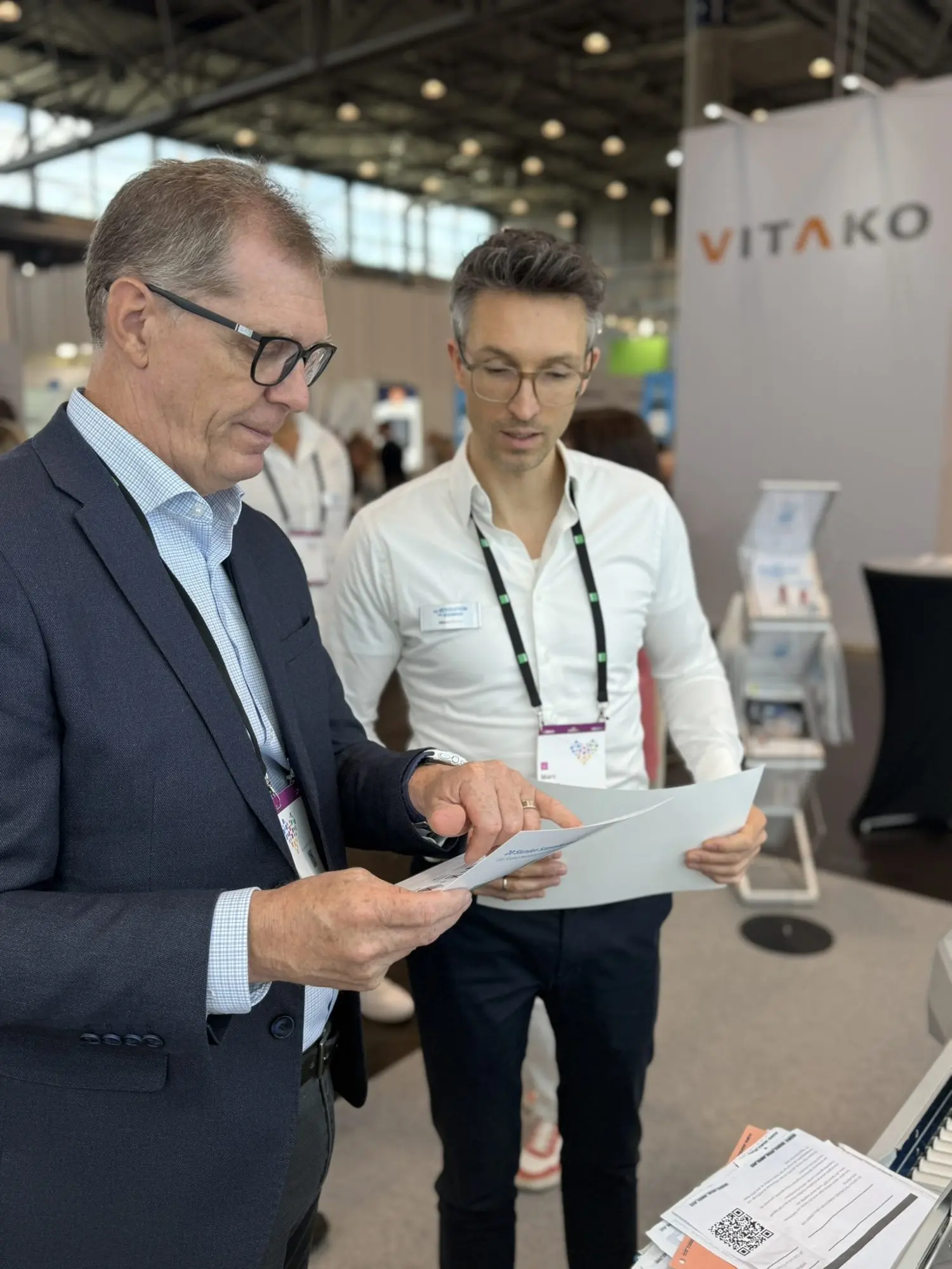 Ein Besucher liest am Stand ein Informationsblatt, daneben ein X-NRW-Mitarbeiter